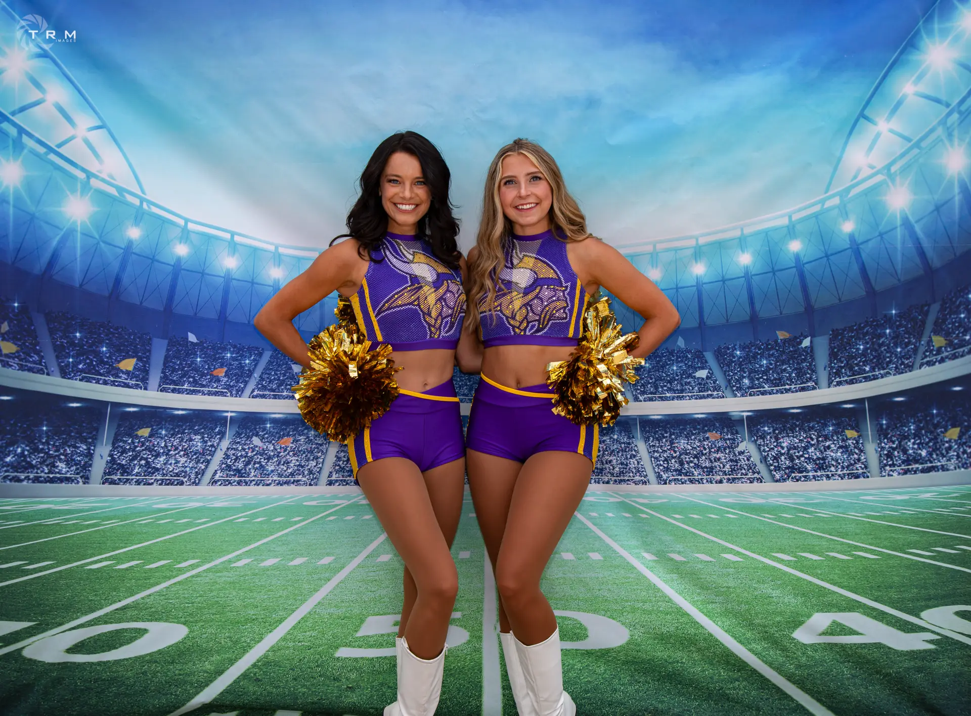 Two Minnesota Vikings cheerleaders stand together, poms at thier hips, wearing a purple top and a cheer skirt with white boots. They are standing infront of a stadium backdrop.